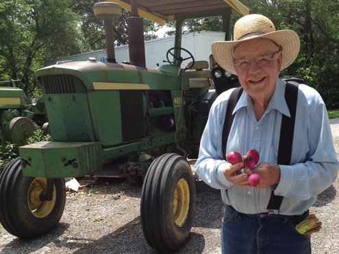 Joe standing in front of a Tractor Holding Radishes